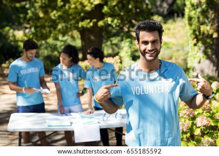 Portrait of smiling volunteer pointing at his t-shirt