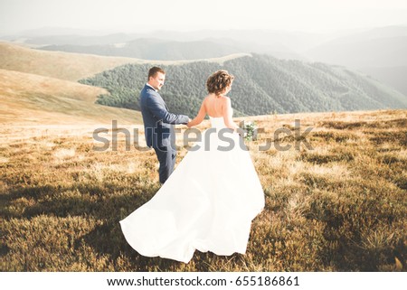 Beautiful gorgeous bride posing to groom and having fun, luxury ceremony at mountains with amazing view, space for text, wedding couple