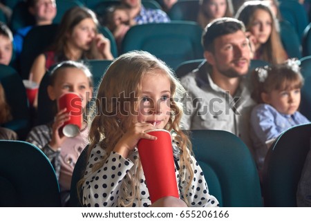 Pretty little girl drinking coke sitting at the movie theatre enjoying watching cartoon copyspace happiness positivity people leisure children child kids kid cuteness innocence entertainment activity.