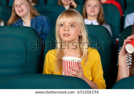 Shot of a cute young blonde haired girl watching a movie at the cinema looking fascinated children kids entertaining activity weekend holidays amazement amusement films activity concept. 