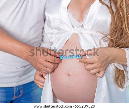 Pregnant woman and her husband touching belly close up. It's a boy