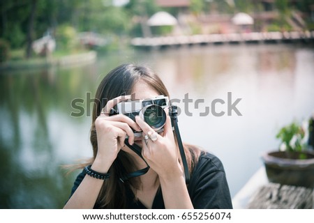 Hipster woman taking photos with retro film camera in outdoor city park,beautiful girl photographed in the old camera