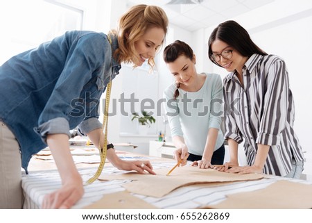 Three female tailors looking at patterns