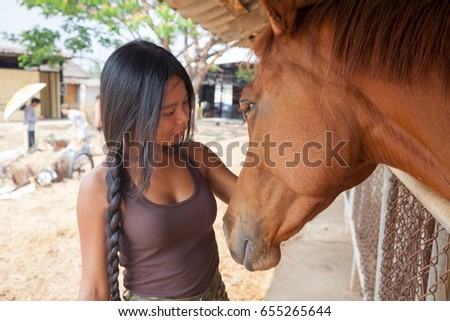 Beautiful elegance woman cowgirl nearby muzzle horse. Has smiling face, brown leather jacket and hat. Has slim body. Portrait nature. People and animals. Equestrian. Close up. American ranch. riding