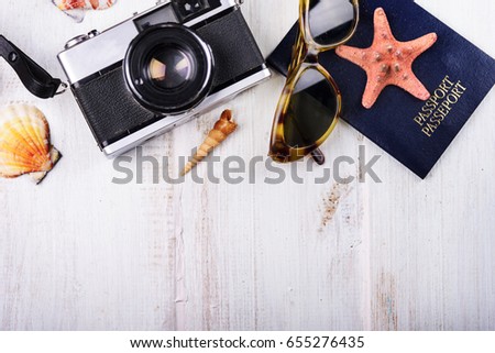 Vintage photo camera, passport, sunglasses and seashells border on wooden white background. Summer holiday design with copyspace. Traveling concept.