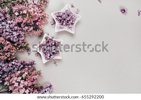 Lilac flowers on grey pastel background in star-shaped ceramics bowls. Flat lay style. Place for your text.