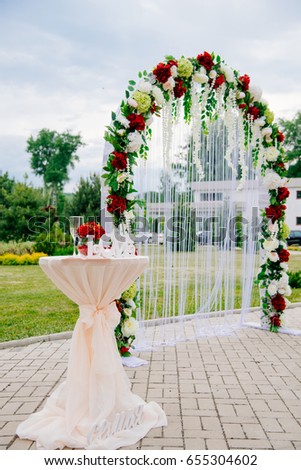 Arch for the wedding ceremony, decorated with cloth flowers and greenery