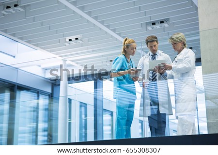 Medical team discussing over digital tablet in corridor at hospital Royalty-Free Stock Photo #655308307