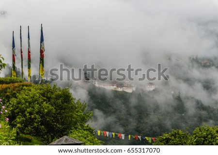 View of Trongsa Dzong with foggy hills, Bumthang, Bhutan, Asia. Traditional holy Buddhist prayer flags.