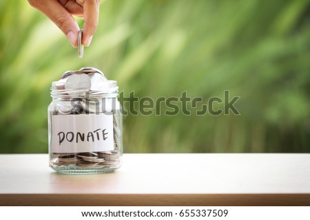 Hand putting Coins in glass jar for giving and donation concept Royalty-Free Stock Photo #655337509