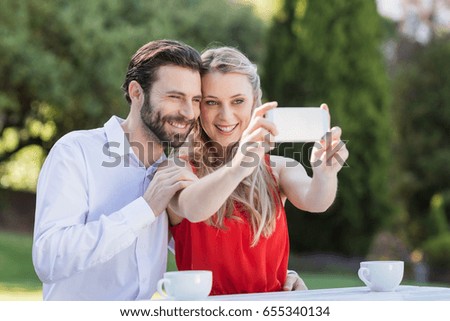 Happy couple taking a selfie on mobile phone in a restaurant