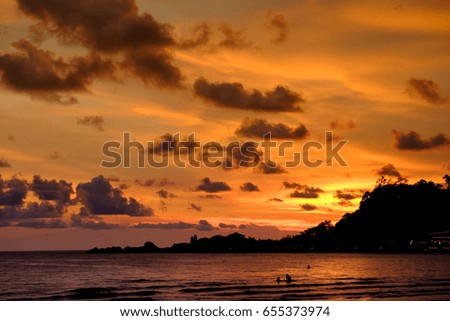The sunset at the beach in summer with the cloudy golden sky and mountain in the background

This picture was intentionally shot as a bit under to strengthen the mood and tone of the photo