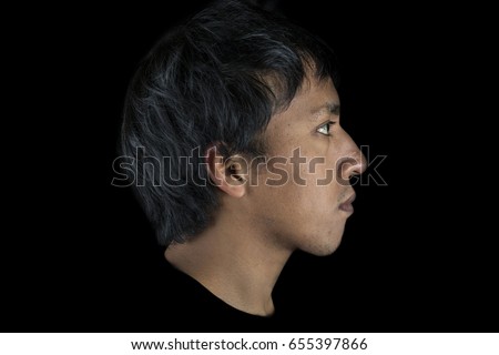 Profile portrait of the head of a young Native American ethnicity man, on black background