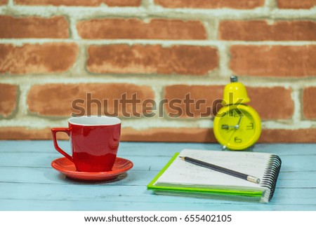 Books, coffee mug, yellow clock Red brick background