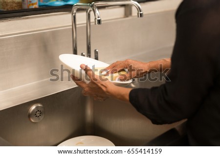 Woman washing the dishes in kitchen sink in the restaurant