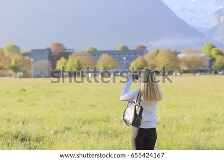 pretty young woman taking photos with smartphone on the mountain view.