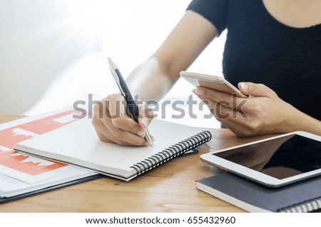 Business, office concept. Woman writing and checking business document on mobile before presentation.