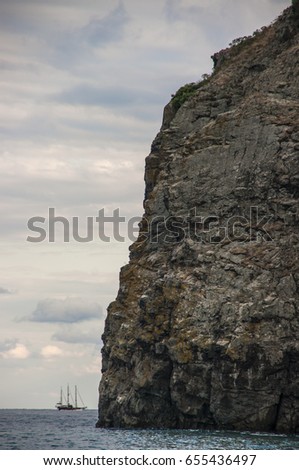 Sailing yacht in the sea bay against the background of the cliff