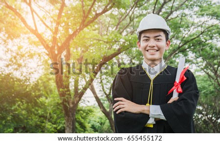 Engineering graduated students holding a diploma and wearing a helmet, smiling happily. Royalty-Free Stock Photo #655455172