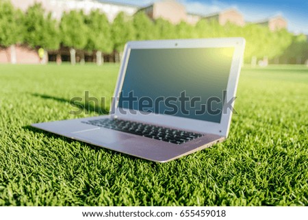 An open laptop on the campus lawn