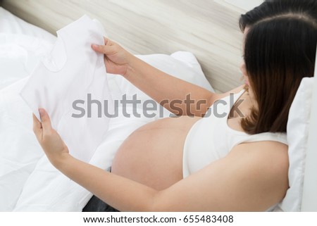 Pregnant woman choosing newborn clothes