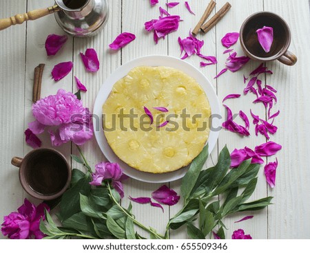 Homemade pineapple tarte Tatin and peony flowers on wooden table. Flat lay.