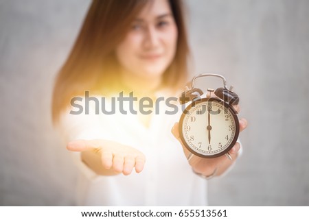 Times to pay the money bill or tax now, It's time to give me something concept, Asian women hand open palm and hold retro clock at 6 o'clock.