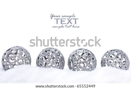 Four silver Christmas ornaments in the snow