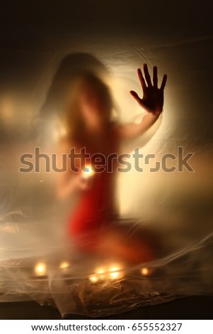 Unfocused girl with candles fire, behind the polyethylene