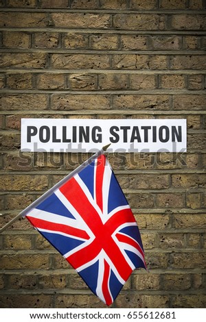 Union Jack flag hanging in front of British election polling station sign posted on classic yellow brick wall in London, UK