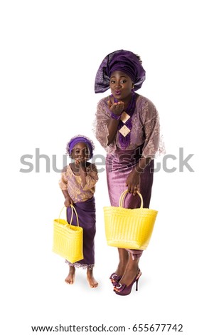 Beautiful African woman and little girl in traditional purple clothing with yellow wicker tote bags showing air kiss. Isolated on the white studio background