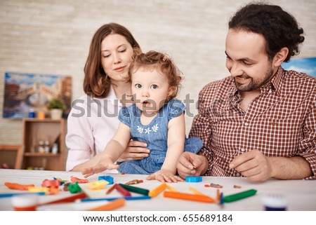 Portrait of happy family having fun playing with cute little daughter at home