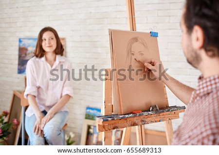Back view portrait of artist sketching models portrait in art workshop, focus on the picture in pencil Royalty-Free Stock Photo #655689313