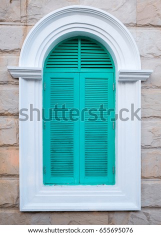 Green arched wooden window on brick wall background.

