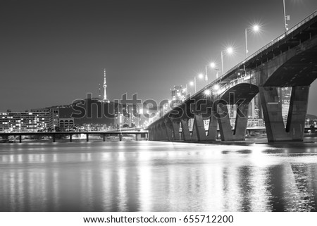 black and white picture of the skyline of downtown Seoul with han river and big bridge with light, Korea at night.