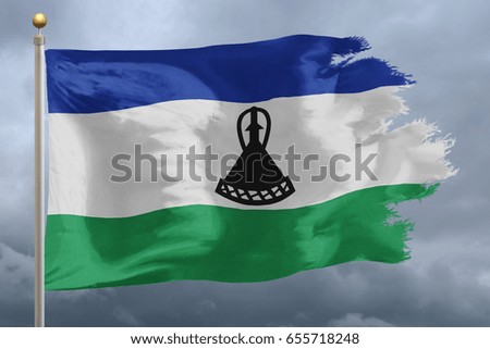 Lesotho Flag with torn edges in front of a stormy sky