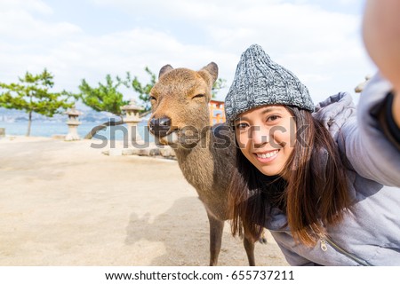 Woman taking selfie with deer in Itsukushima
