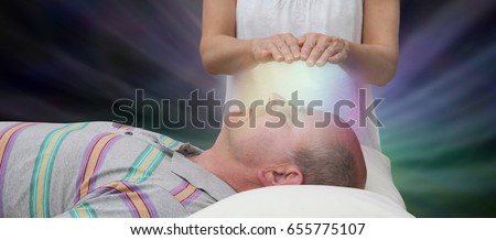 Channeling Healing Energy - female with hands held six inches above a male patient's face displaying colored light on a dark background
 Royalty-Free Stock Photo #655775107