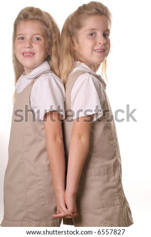 twin school girls vertical holding hands back