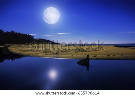 Lonely sandy beach between the river and the sea , with full moon on the sky. The picture taken on the Saulkrasti sandy beach, Latvia.