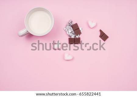 Cup of hot milk with marshmallows and chocolate on pink table, top view