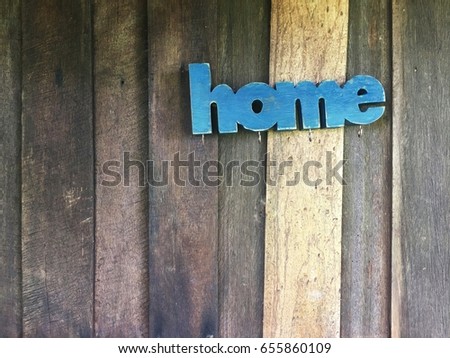 A blue sign home on old wooden house wall.