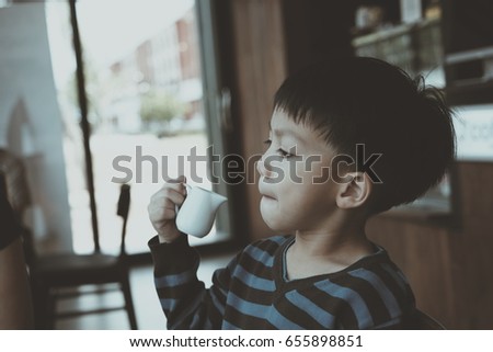 Little boy drinking milk in cafe, vintage color style