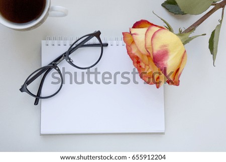 Notebook mock up for artwork with red and yellow rose, glasses and cup of black coffee. Top view. Place for text. Fresh flower