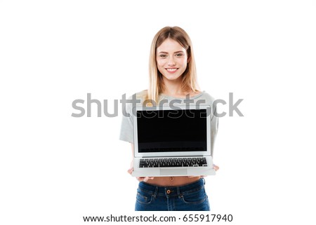 Young smiling confident woman showing laptop computer with blank screen and looking camera isolated over white