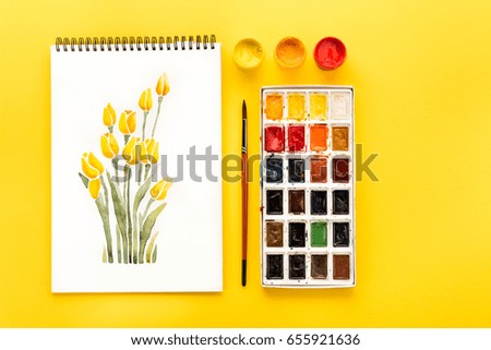 top view of drawing of flowers, paints and brush on yellow, springtime concept
