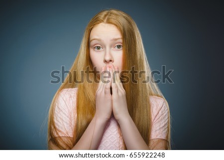 Little girl with astonished expression while standing against grey background