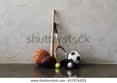 Close-up view of various balls and sports equipment near grey wall