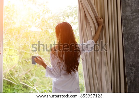 wake up :Woman in the morning holding a cup of tea or coffee and looking at the sunrise standing near the window in her home Royalty-Free Stock Photo #655957123