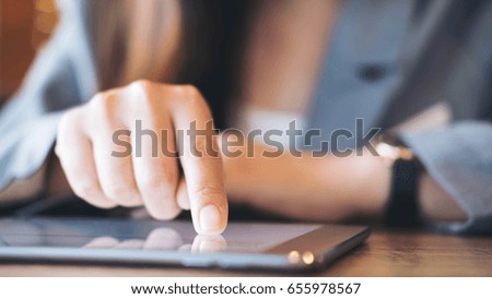 A business woman's hand pointing , touching and using tablet with blur background in cafe